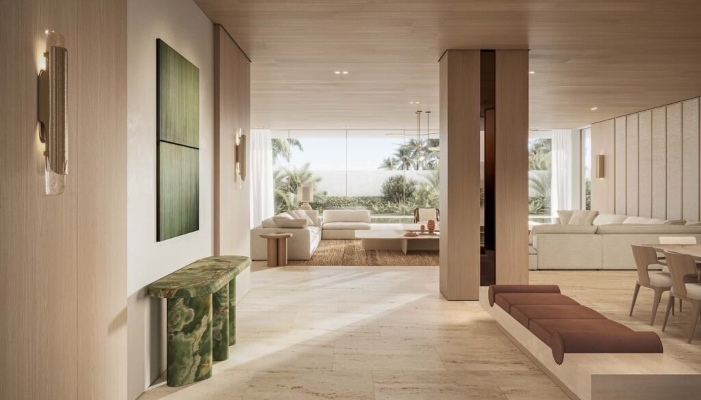 Bright, open-plan luxury living room interior with travertine flooring, light wood accents, marble console, and floor-to-ceiling garden views in Eden Hills Dubai.